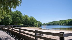 A wooden deck with a view of a lake and forest. - Quaint Holiday Home with Garden (Payzac)