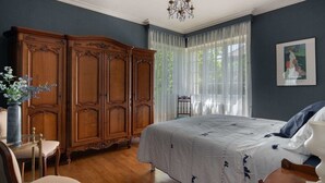 A bedroom with a large bed, wooden wardrobe, and a chandelier. - Quaint Holiday Home with Garden (Payzac)