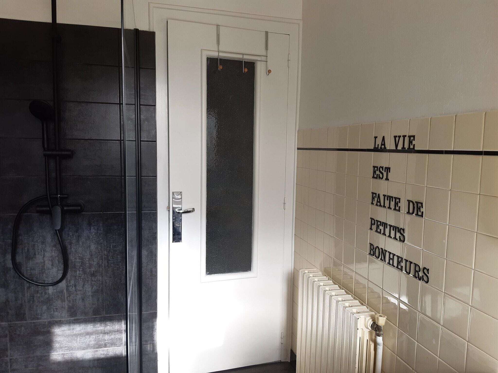 Ein Badezimmer mit Dusche, einer Tür und einer mit Fliesen verkleideten Wand mit Schrift.