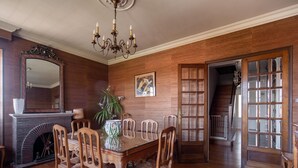 A dining room with a wooden table, chairs, a chandelier, a fireplace, and a large mirror. - Quaint Holiday Home with Garden (Payzac)