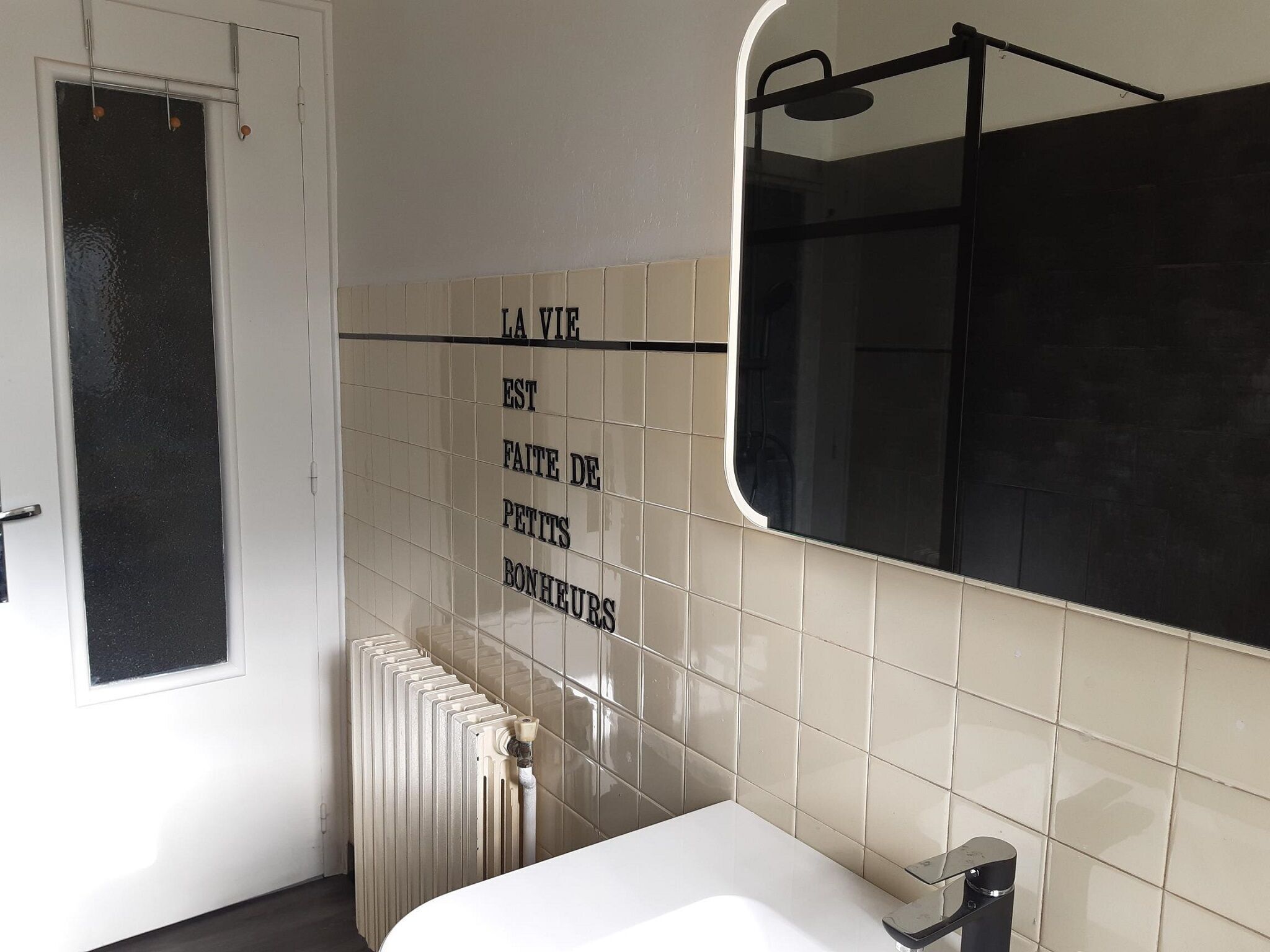Une salle de bain avec un lavabo blanc, un miroir, un porte-serviettes et un radiateur.