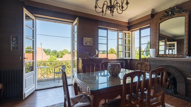 A dining room with a glass table, wooden chairs, a chandelier, and a large mirror. - Quaint Holiday Home with Garden (Payzac)