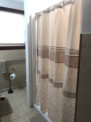 Ein Badezimmer mit Duschvorhang, Toilettenpapierhalter und Handtuchhalter.