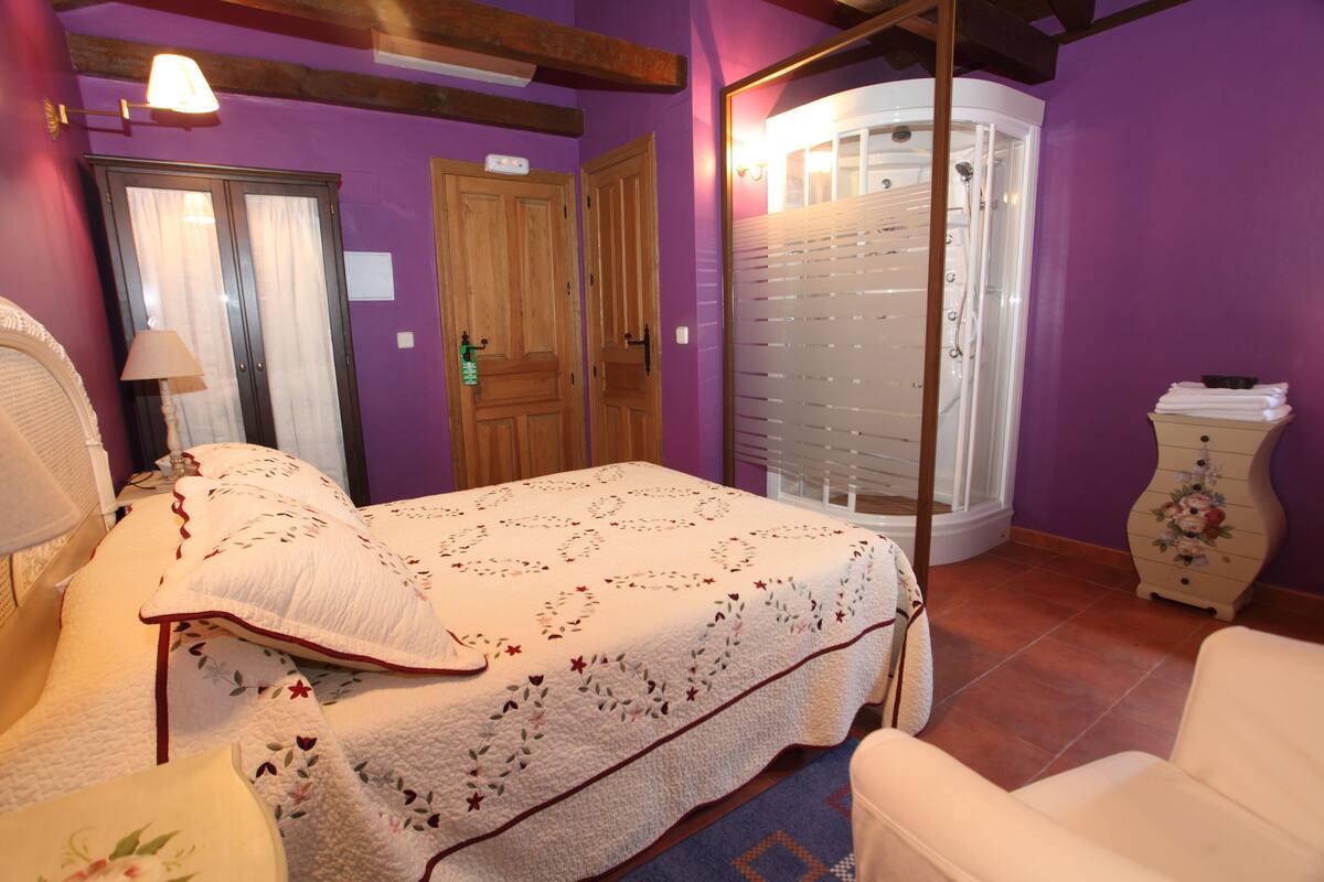 Un dormitorio con cama, una silla, un tocador y un vestidor.