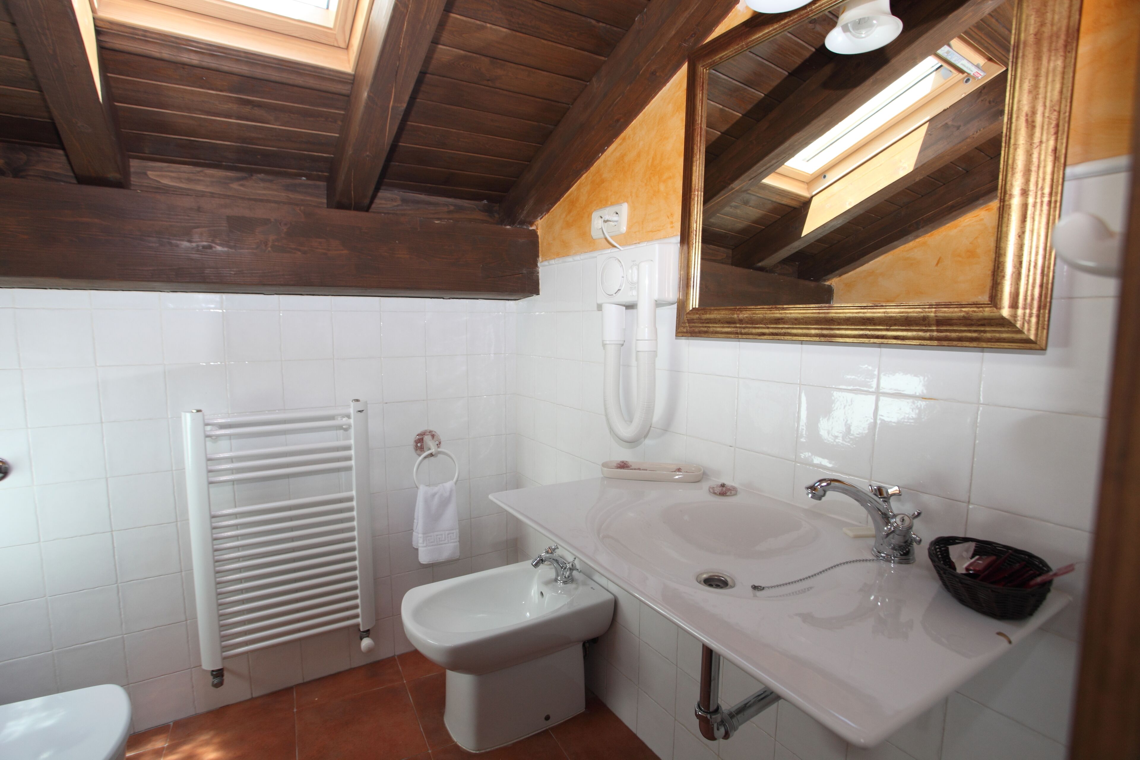 Un baño con lavamanos blanco, un bidé, toallero y un espejo.