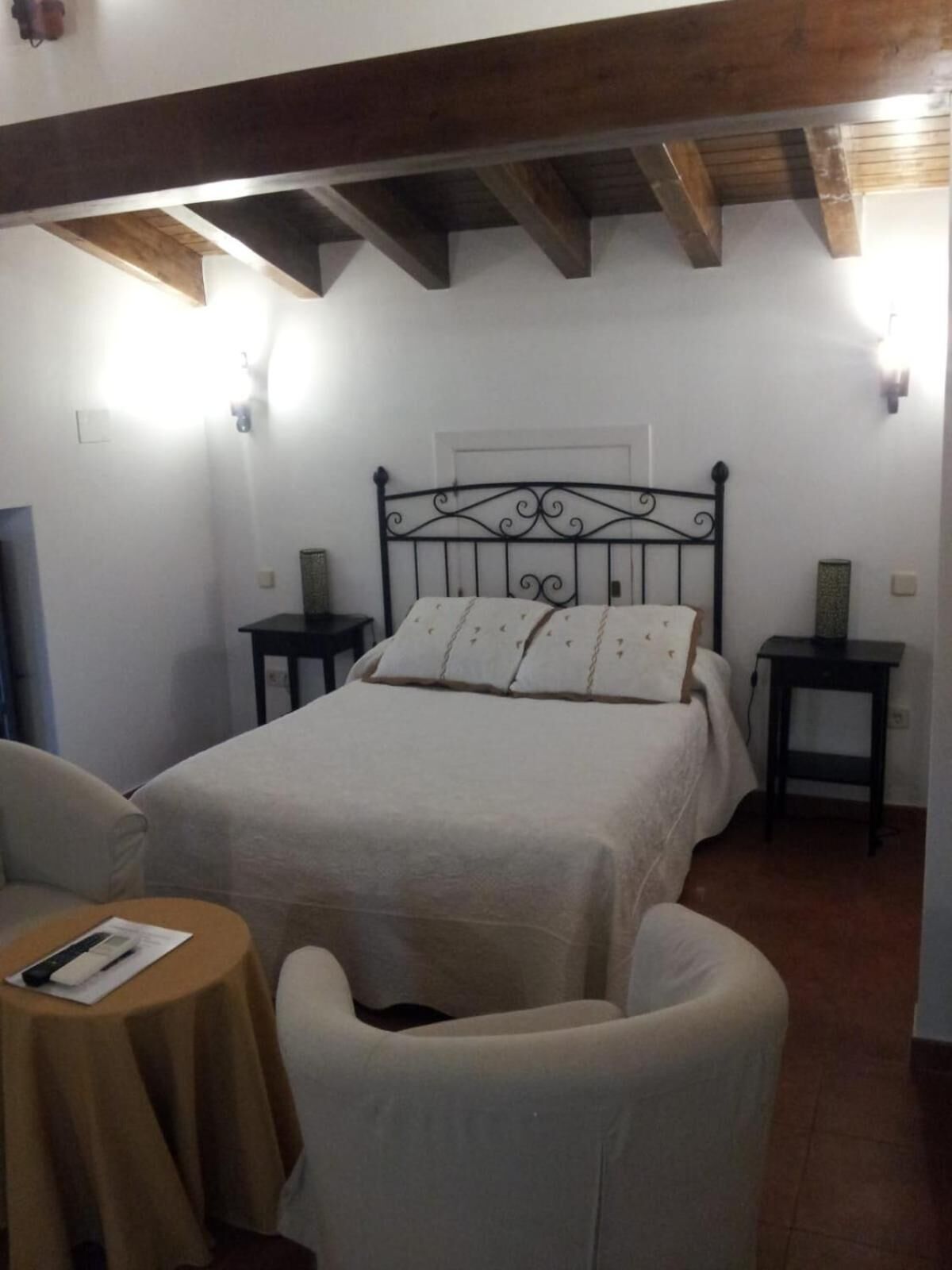 Ein Schlafzimmer mit einem Bett, zwei Nachttischen, einem Sessel und einem kleinen Tisch.