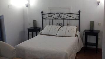 Ein Schlafzimmer mit einem Bett, zwei Nachttischen, einem Sessel und einem kleinen Tisch.
