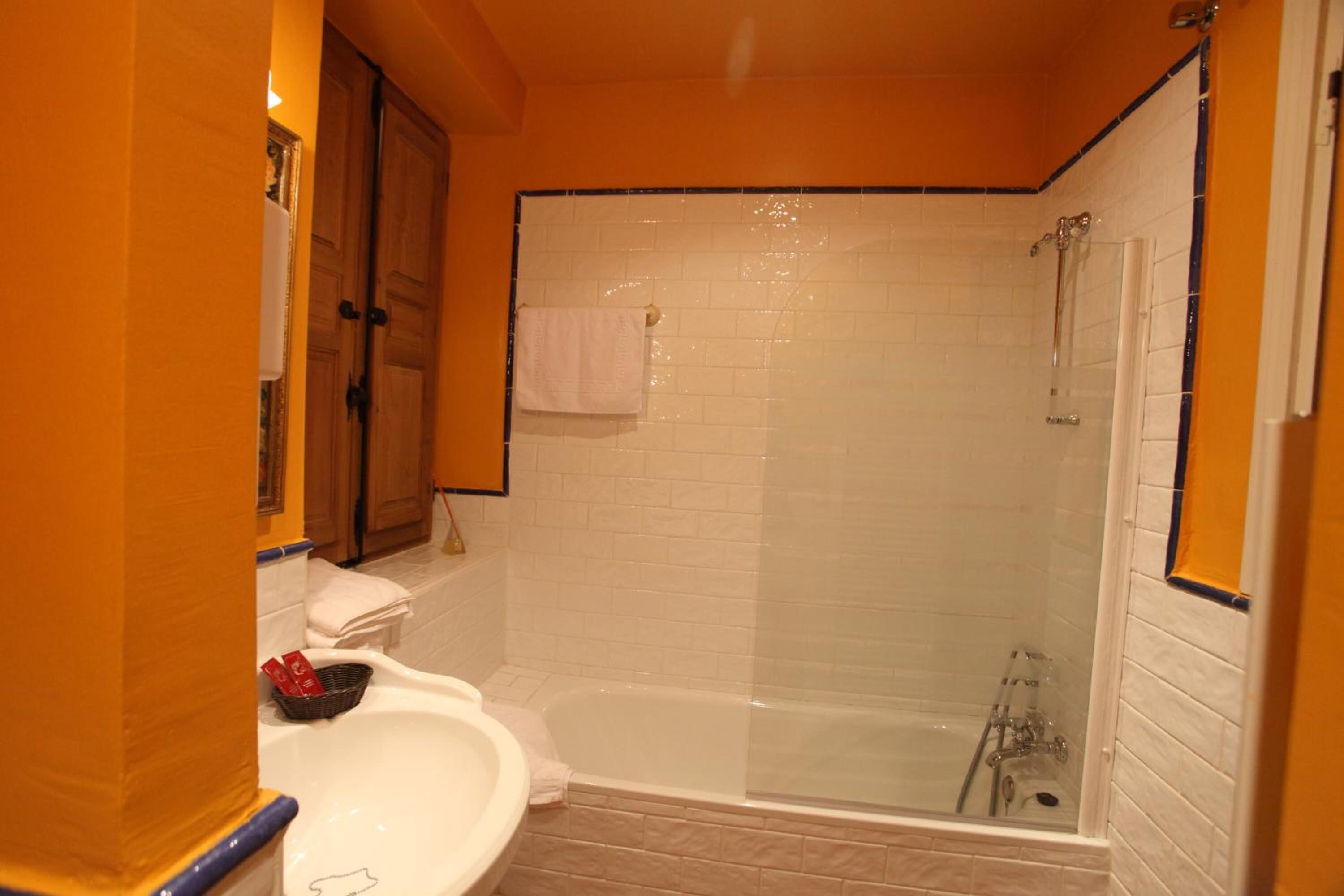 A bathroom with a white bathtub, a glass-enclosed shower, and a sink with a mirror.