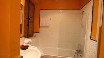 A bathroom with a white bathtub, a glass-enclosed shower, and a sink with a mirror.