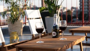 A wooden table with two glasses of red wine and a bottle of Martini wine.