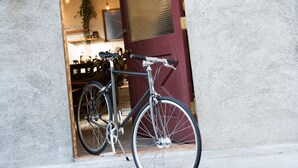 A bicycle parked outside a building with a sign reading "BIKE BED EAST TOKYO".