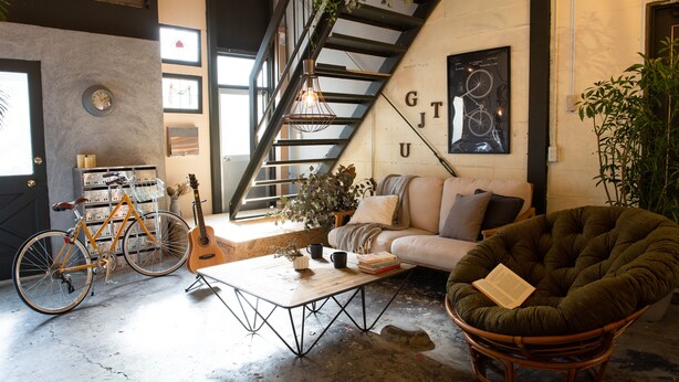 A cozy living space with a staircase, a sofa, a chair, a coffee table, a bicycle, and a guitar.