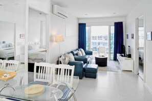 Un soggiorno moderno con divano, tavolo da pranzo e sedie. Include un balcone con vista sugli edifici.