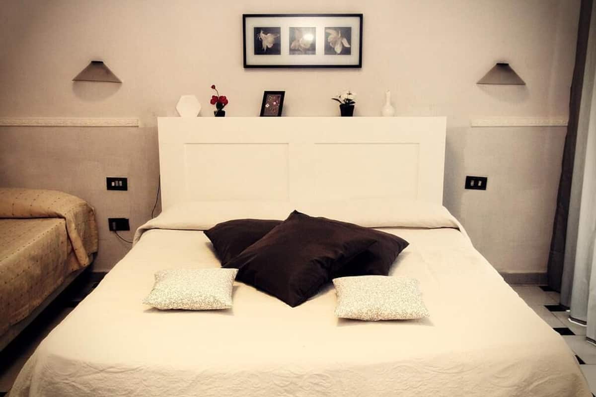 A neatly made bed with a white headboard, two pillows, and a framed picture above it.