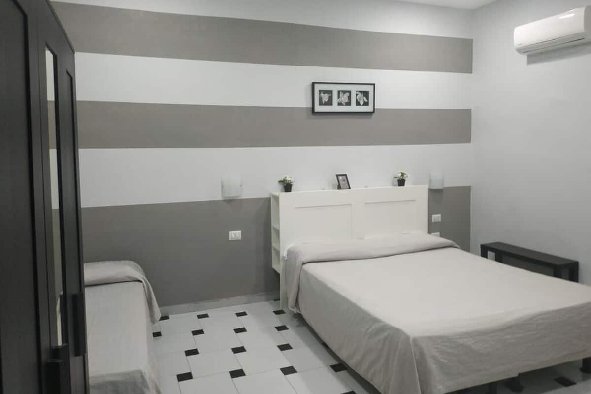 A bedroom with a bed, bedside tables, a wardrobe, and a checkered floor.