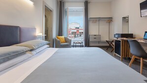 A modern hotel room with a large bed, a desk with a computer, a chair, a small table, and a wardrobe. - Centro Storico via Sassari Accommodation (Cagliari)