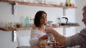 A breakfast setting with a wooden table, a coffee maker, and a fruit plate. - Centro Storico via Sassari Accommodation (Cagliari)