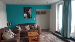 Un saló amb un sofà marró, una taula de centre de fusta i parets de color blau verd.