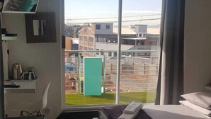 Habitació d'hotel moderna amb una finestra gran, un llit, una taula de treball i una cadira.