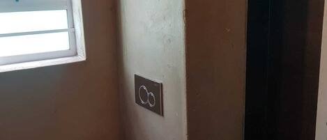 A small bathroom with a toilet, a window, and a shower area.