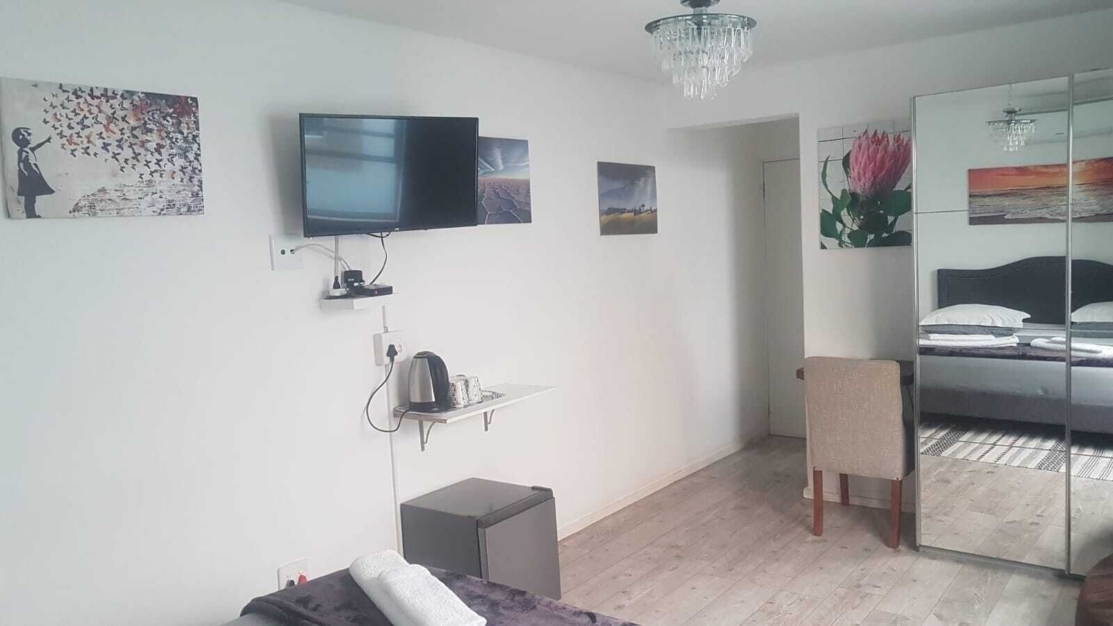 A modern bedroom with a bed, a TV, a small desk, and a chair.