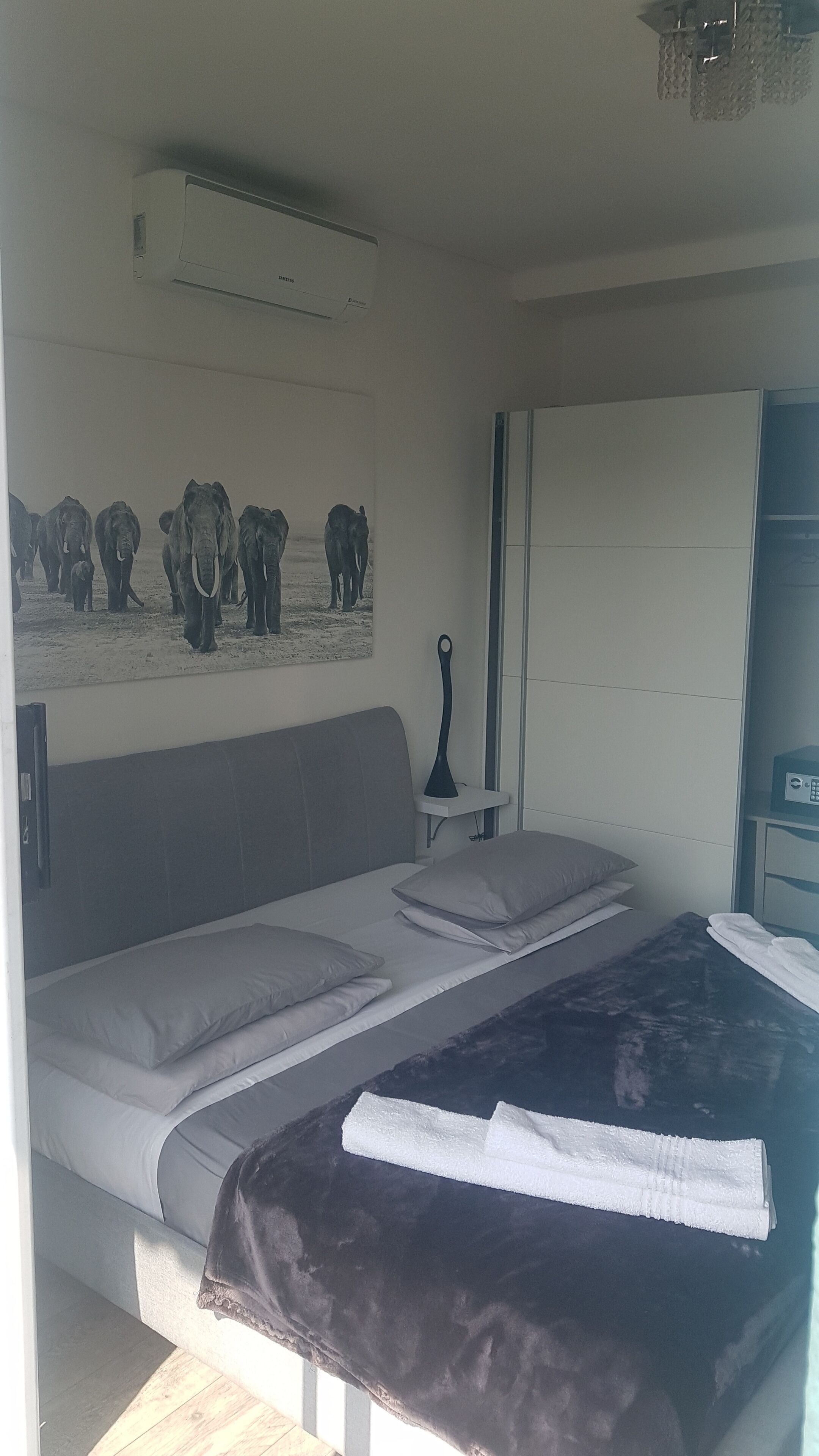 Ein Schlafzimmer mit einem Bett, einer Couch, einer Wand-Klimaanlage, einem Elefantenbild und einer Tür.