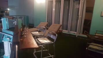 A bar area with a wooden counter, metal chairs, and a bottle of wine.