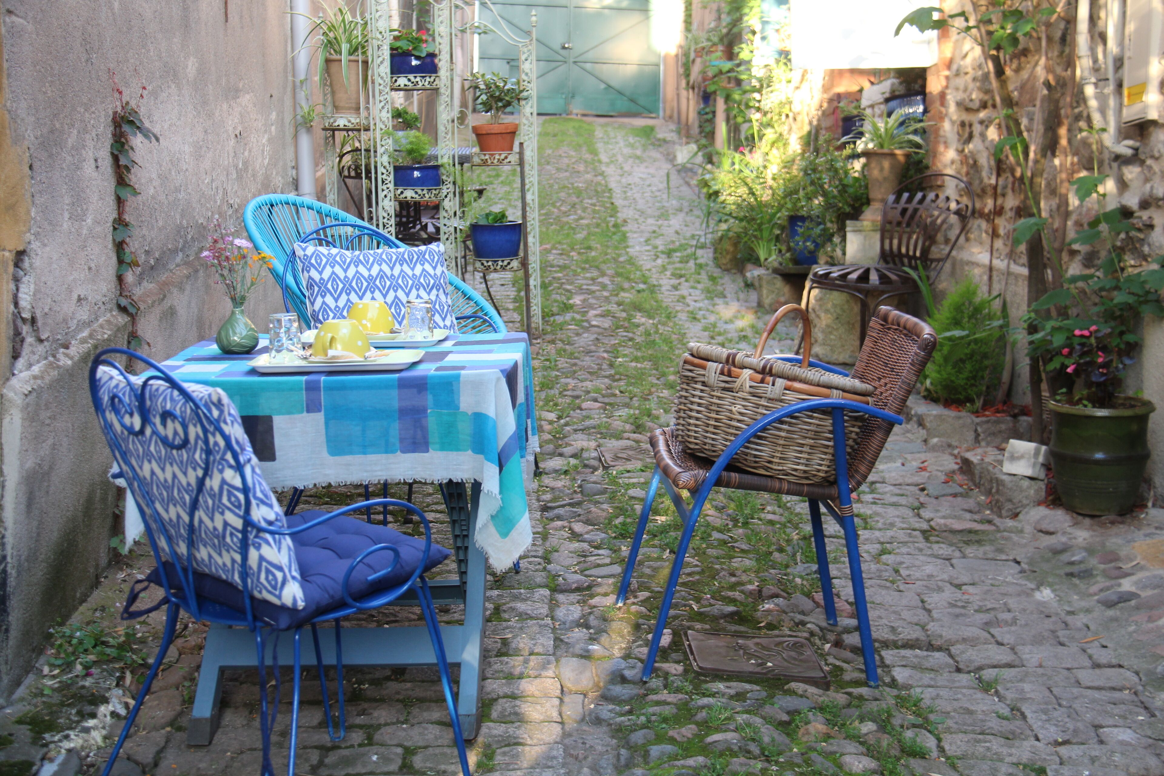 A narrow cobblestone alley with a table and chairs set up for dining.