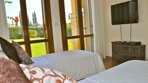 Un dormitorio con dos camas, televisión y vistas a un jardín.
