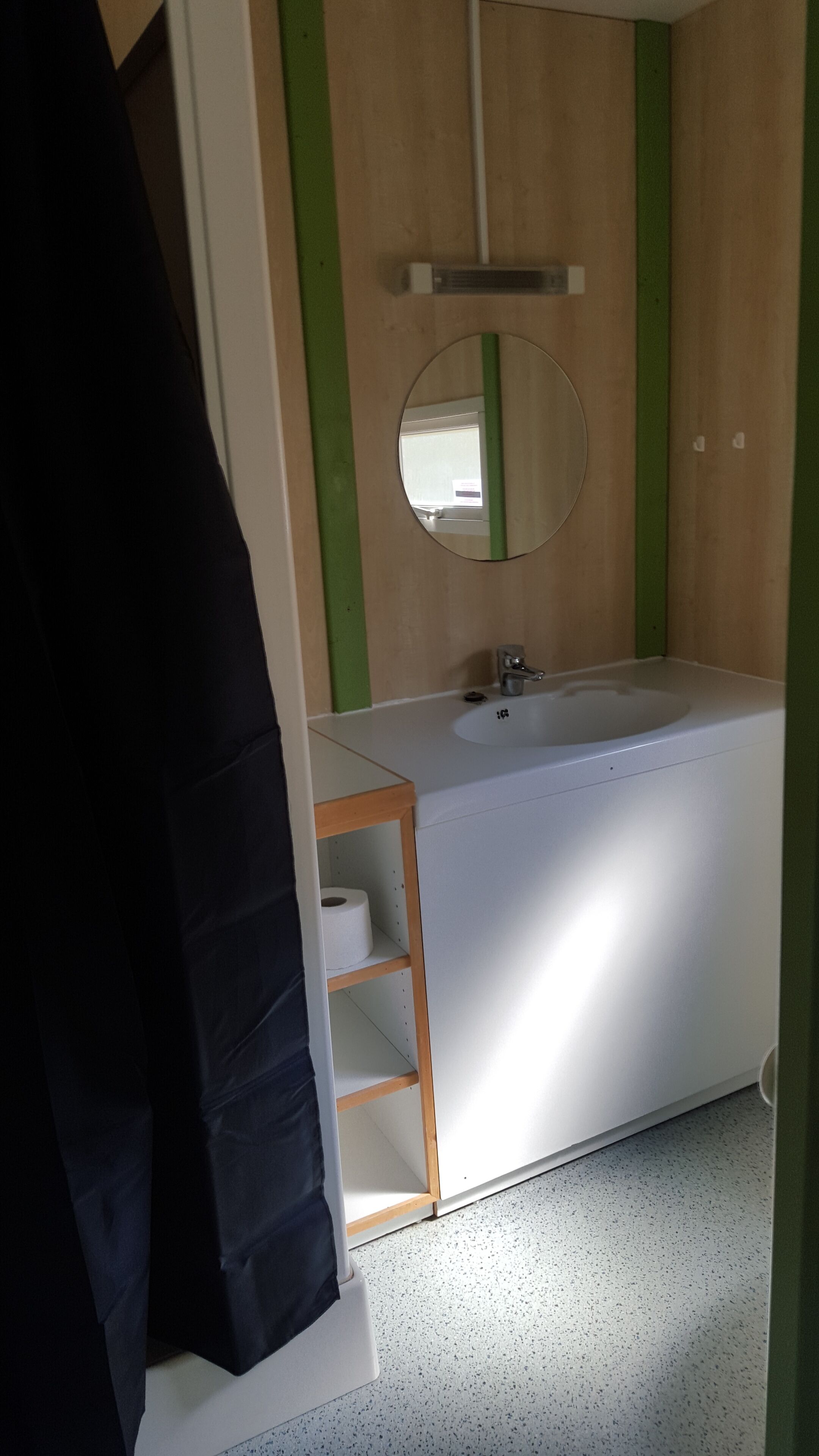 A bathroom with a white bathtub, a wooden shelf with a roll of toilet paper, and a mirror on the wall.