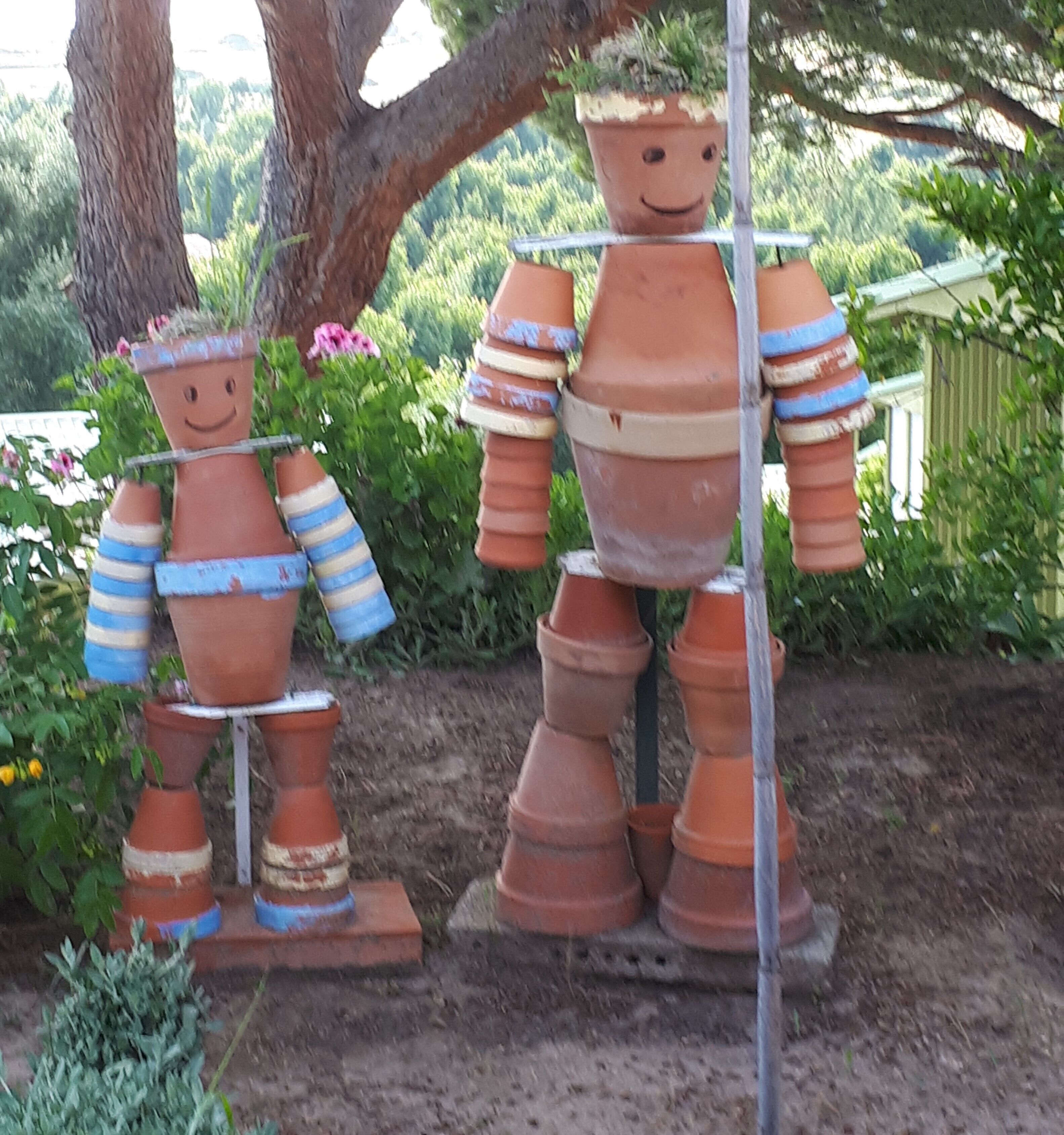 Sculptures en terre cuite représentant des personnages dans un décor de jardin.