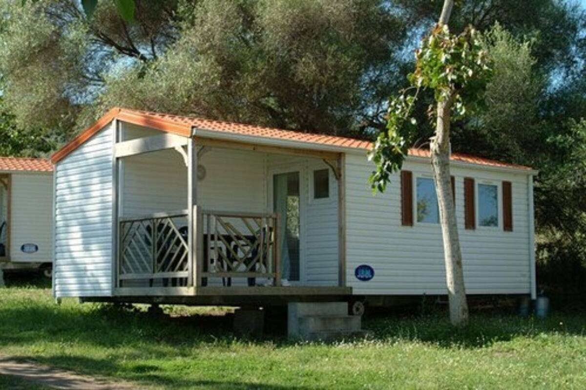 A mobile home with a covered porch and a small window.