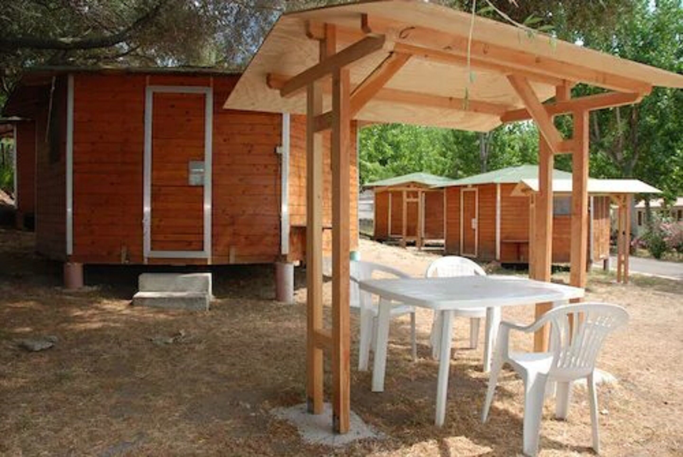 Una cabaña de madera con un espacio de estar techado al aire libre y una mesa.