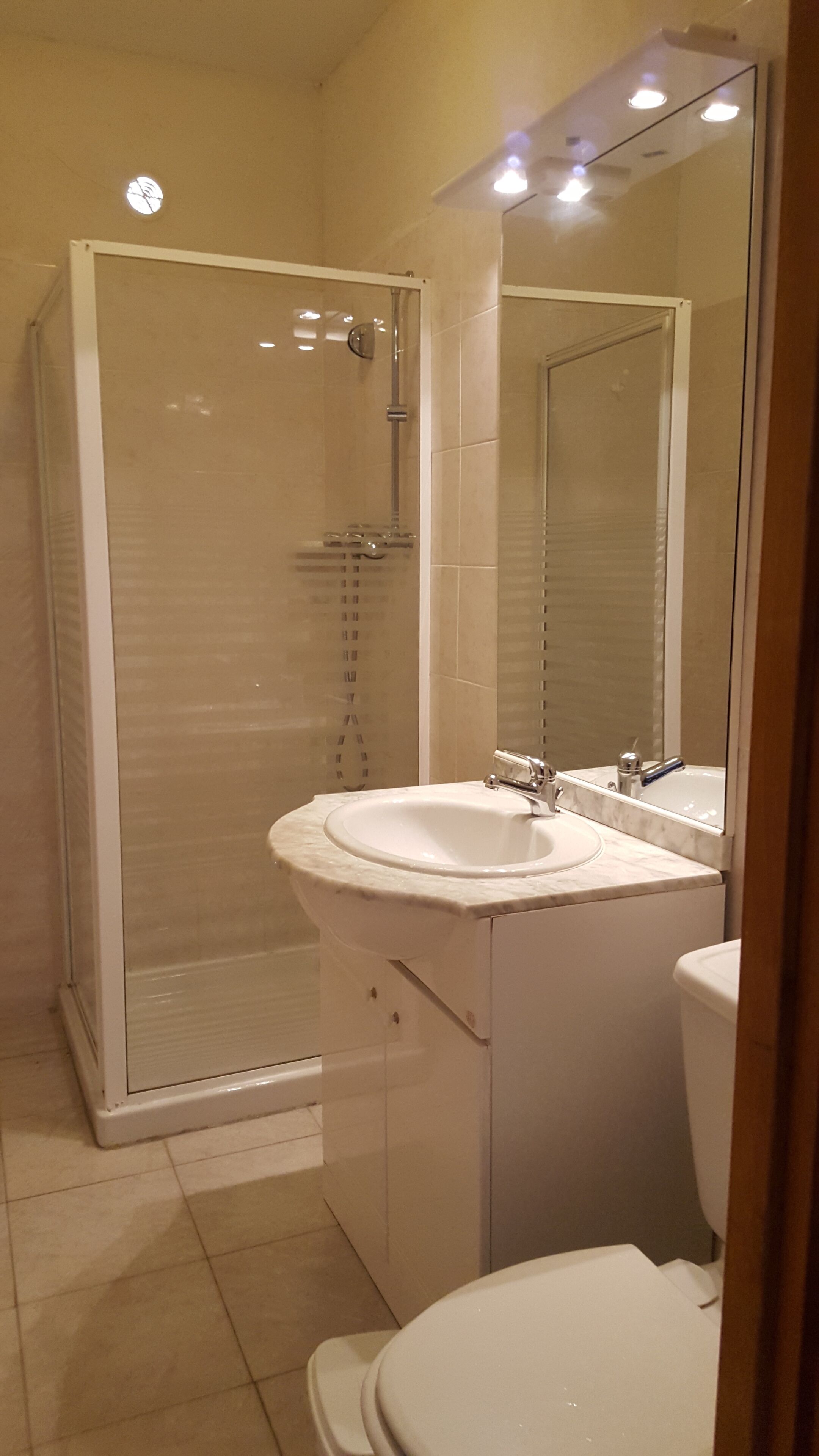 Une salle de bain avec une douche à parois de verre, un lavabo et des toilettes.