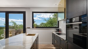 Una cocina moderna con una isla grande, armarios negros y vistas al exterior.