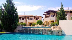 A resort with a swimming pool, multiple-story buildings, and a rocky landscape. - Apartment DC01 - Kalypso (Kouklia)