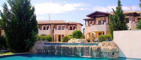Un resort con piscina, edificios de varios pisos y un paisaje rocoso.