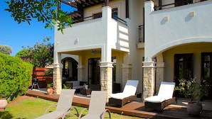 A two-story building with a patio area featuring lounge chairs and a barbecue setup. - Apartment DC01 - Kalypso (Kouklia)