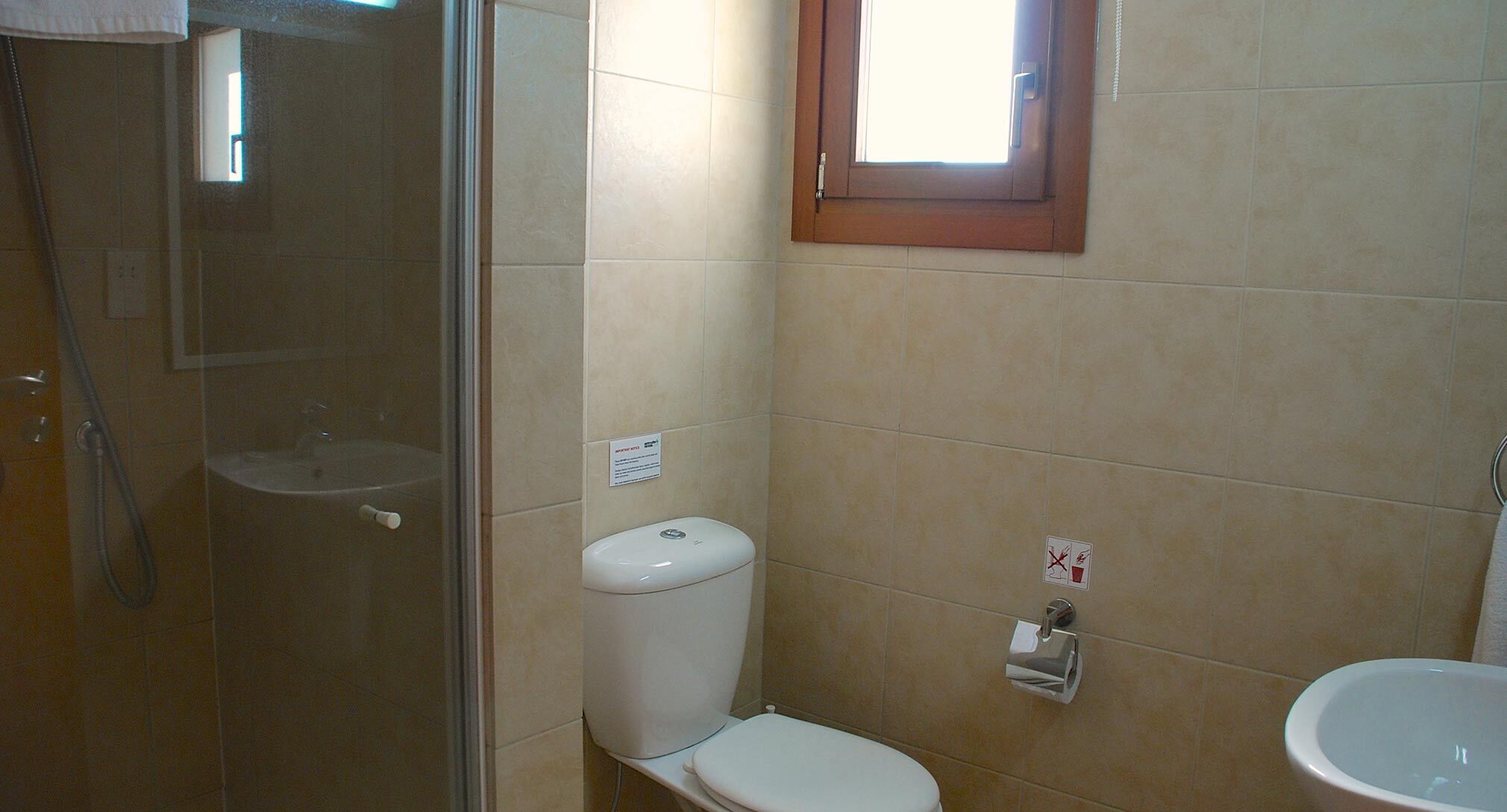 A small bathroom with a toilet, a sink, and a shower.