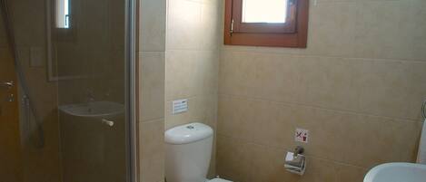 A small bathroom with a toilet, a sink, and a shower.