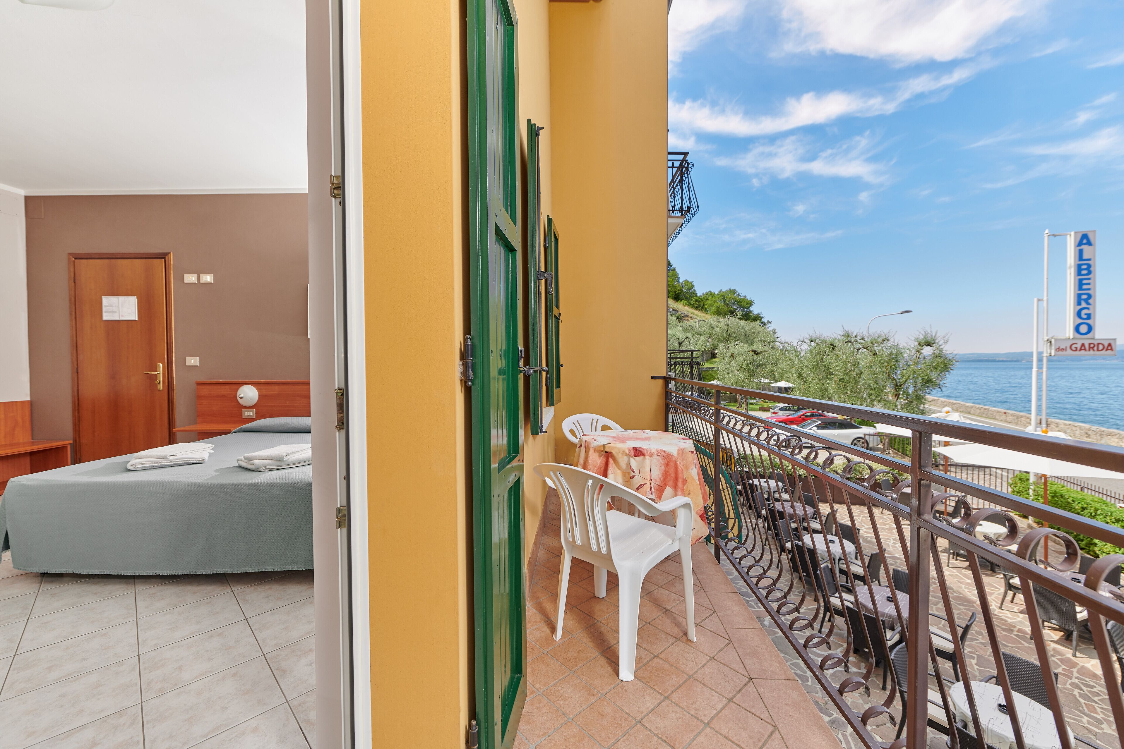 A balcony with a view of the sea, a bed, and a table with chairs.