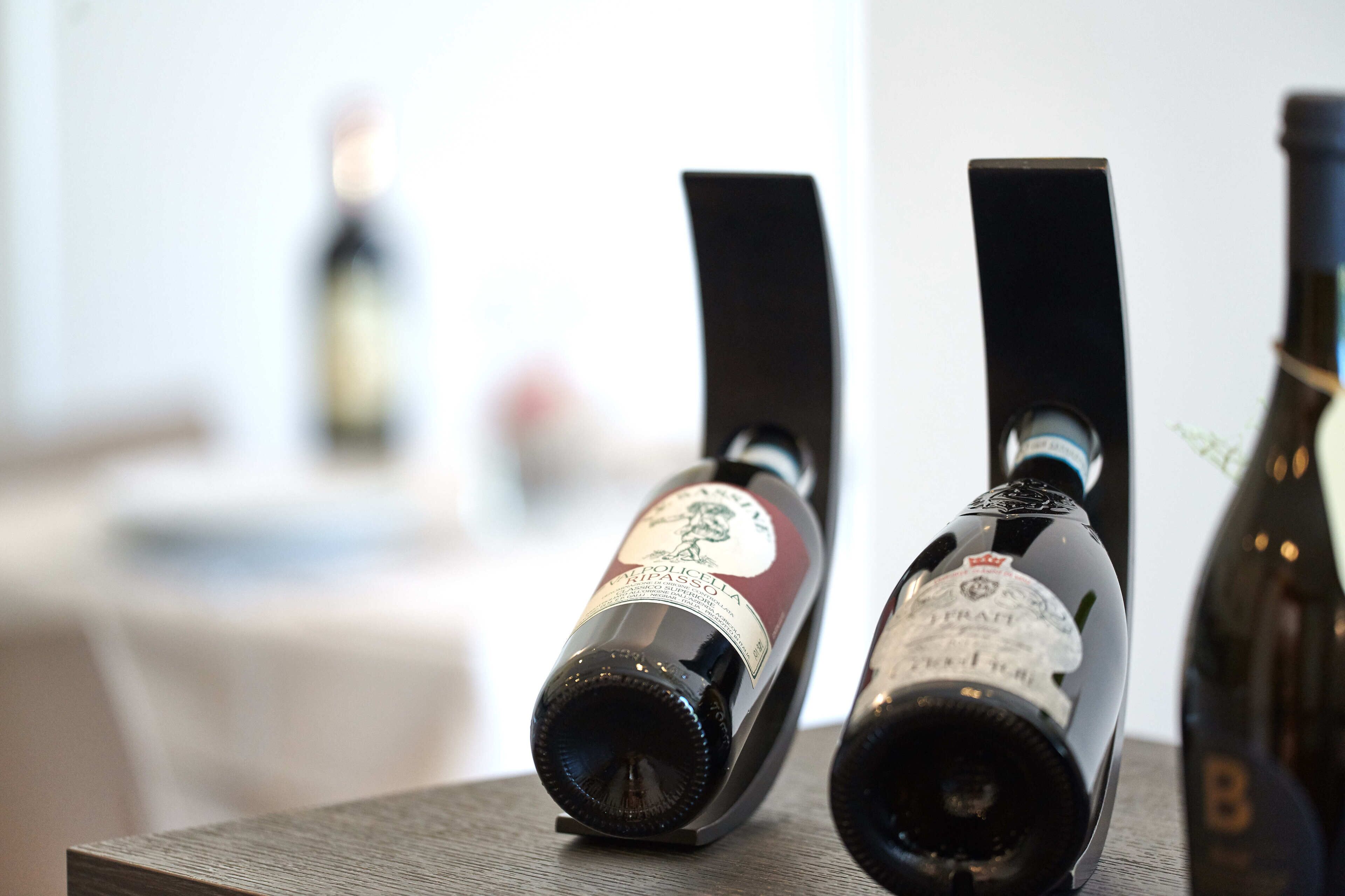 Dos botellas de vino sobre una superficie de madera con fondo desenfocado.