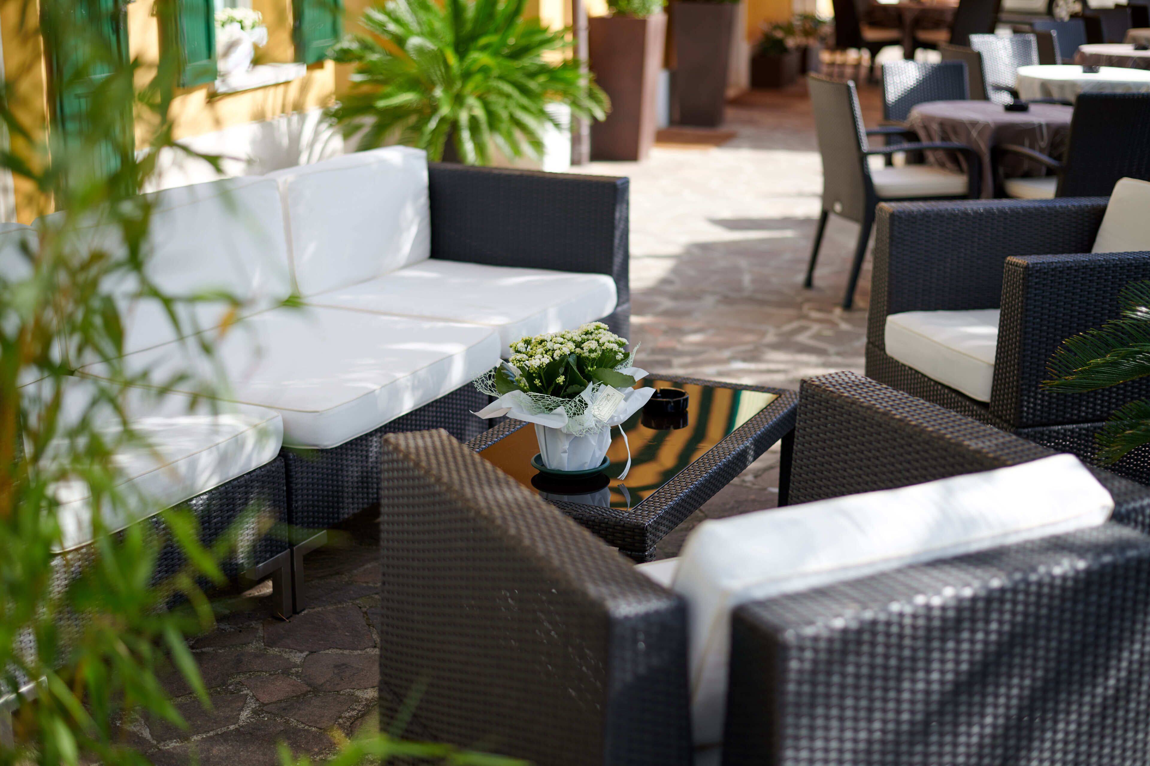 An outdoor seating area with wicker furniture and a small table with a plant.