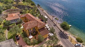A coastal property with a paved road, a beach, and a clear view of the sea. - Albergo Del Garda (Torri del Benaco)