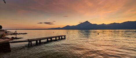 Une vue magnifique sur le coucher de soleil, avec un lac paisible et une jetée en bois qui s’avance dans l’eau.