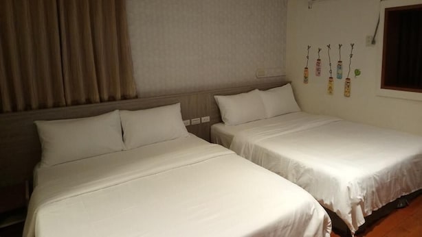 A hotel room with two beds, a window, and a wall-mounted air conditioner. - Fu Xing Homestay (Magong)