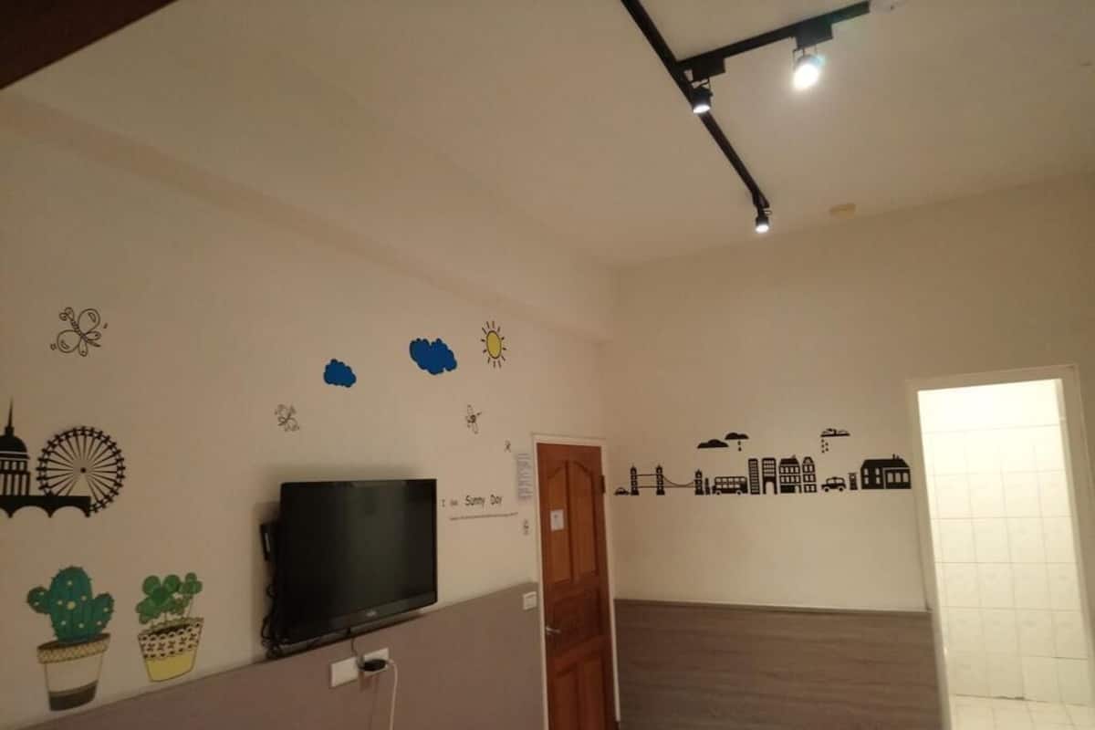 A room with a TV on a stand, a door, and a wall with cityscape decals.