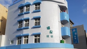 A building with a curved facade, multiple balconies, and a prominent star design on the lower part. - Fu Xing Homestay (Magong)