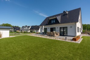 A modern house with a sloped roof, large windows, and a well-maintained lawn.