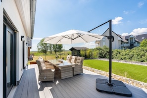 An outdoor patio with wicker furniture and a large umbrella.